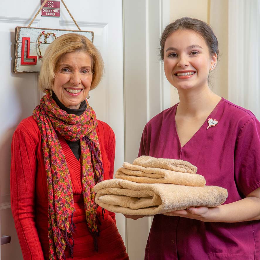 A team member delivering fresh linens to a resident at The Oaks